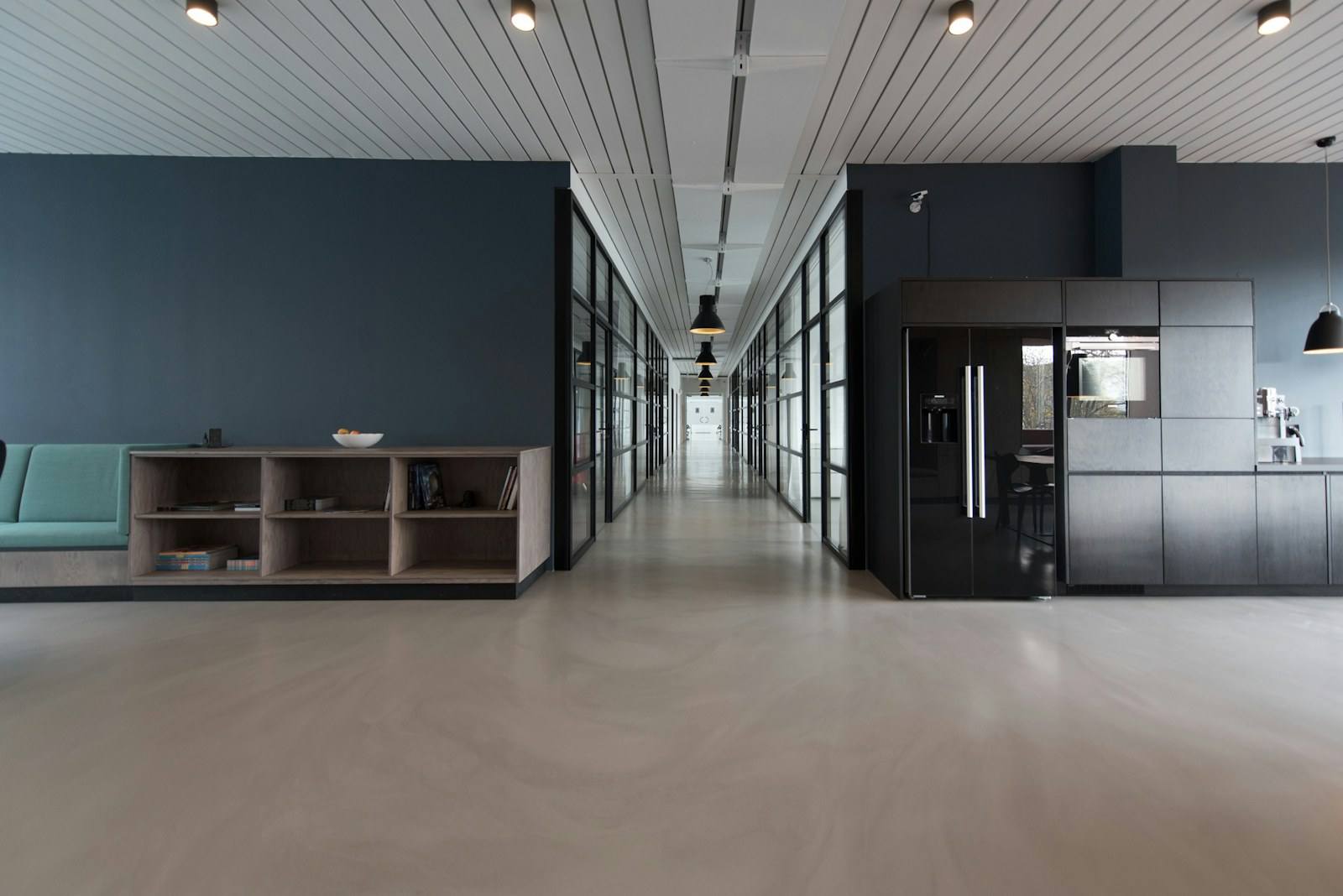 A modern office interior with glass-walled corridors and lounge seating